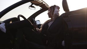 Νέα ελκυστική συνεδρίαση κοριτσιών, που χαλαρώνει στο μαύρο σπορ αυτοκίνητο της και που κρατά το κινητό τηλέφωνο Φορά τα mosern γ απόθεμα βίντεο Νέα ελκυστική συνεδρίαση κοριτσιών, που χαλαρώνει στο μαύρο σπορ αυτοκίνητο της και που κρατά το κινητό τηλέφωνο Φορά τα mosern γ απόθεμα βίντεο