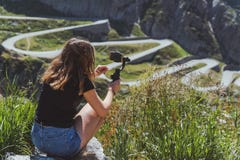 Νέα μαγνητοσκόπηση γυναικών ο δρόμος tremola στο SAN gotthard που χρησιμοποιεί ένα smartphone και έναν αναρτήρα στοκ φωτογραφίες με δικαίωμα ελεύθερης χρήσης Νέα μαγνητοσκόπηση γυναικών ο δρόμος tremola στο SAN gotthard που χρησιμοποιεί ένα smartphone και έναν αναρτήρα στοκ φωτογραφίες με δικαίωμα ελεύθερης χρήσης