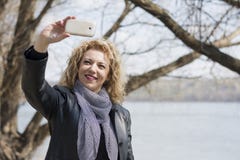 Νέα σγουρή ξανθή γυναίκα που παίρνει την εικόνα της στοκ φωτογραφία με δικαίωμα ελεύθερης χρήσης Νέα σγουρή ξανθή γυναίκα που παίρνει την εικόνα της στοκ φωτογραφία με δικαίωμα ελεύθερης χρήσης