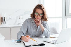 Νέα συγκεντρωμένη επιχειρηματίας στα γυαλιά και το ριγωτό πουκάμισο wo στοκ φωτογραφία Νέα συγκεντρωμένη επιχειρηματίας στα γυαλιά και το ριγωτό πουκάμισο wo στοκ φωτογραφία