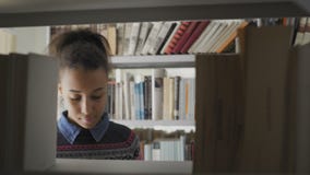 Νέα όμορφη γυναίκα αφροαμερικάνων στη σχολική βιβλιοθήκη απόθεμα βίντεο Νέα όμορφη γυναίκα αφροαμερικάνων στη σχολική βιβλιοθήκη απόθεμα βίντεο