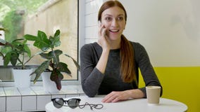 Νέα όμορφη γυναίκα με τη συνεδρίαση ponytail στον καφέ, που μιλά στο τηλέφωνο, συγκινημένο και έκπληκτο απόθεμα βίντεο Νέα όμορφη γυναίκα με τη συνεδρίαση ponytail στον καφέ, που μιλά στο τηλέφωνο, συγκινημένο και έκπληκτο απόθεμα βίντεο
