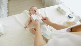 Νέες μεταβαλλόμενες πάνες μητέρων στο γιο μωρών 3 μηνών της που βρίσκεται στο μεταβαλλόμενο πίνακα Νέες μεταβαλλόμενες πάνες μητέρων στο γιο μωρών 3 μηνών της που βρίσκεται στο μεταβαλλόμενο πίνακα