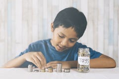 Νέο αγόρι που μετρά τα νομίσματα/την αποταμίευσή του για να αγοράσει τα παιχνίδια ονείρου Στοκ Εικόνες Νέο αγόρι που μετρά τα νομίσματα/την αποταμίευσή του για να αγοράσει τα παιχνίδια ονείρου Στοκ Εικόνες