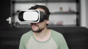 Νέο γενειοφόρο άτομο hipster που χρησιμοποιεί την επίδειξη κασκών VR του για την προσοχή του βίντεο 360 καθμένος στον καναπέ και Νέο γενειοφόρο άτομο hipster που χρησιμοποιεί την επίδειξη κασκών VR του για την προσοχή του βίντεο 360 καθμένος στον καναπέ και