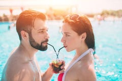 Νέο ζεύγος από την πισίνα Άνδρας και γυναίκες που πίνουν τα κοκτέιλ στο νερό στοκ εικόνα Νέο ζεύγος από την πισίνα Άνδρας και γυναίκες που πίνουν τα κοκτέιλ στο νερό στοκ εικόνα