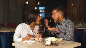 Νέο ζεύγος που έχει το γεύμα σε ένα εστιατόριο Ένας νεαρός άνδρας ταΐζει τη φίλη του με cheesecake και γελά φιλμ μικρού μήκους Νέο ζεύγος που έχει το γεύμα σε ένα εστιατόριο Ένας νεαρός άνδρας ταΐζει τη φίλη του με cheesecake και γελά φιλμ μικρού μήκους