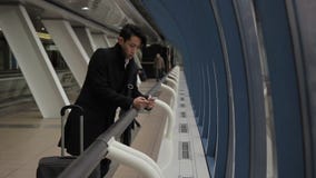 Νέο κορεατικό τηλέφωνο χρήσεων επιχειρηματιών, που στέκεται στον αερολιμένα που χτίζει στο εσωτερικό απόθεμα βίντεο Νέο κορεατικό τηλέφωνο χρήσεων επιχειρηματιών, που στέκεται στον αερολιμένα που χτίζει στο εσωτερικό απόθεμα βίντεο