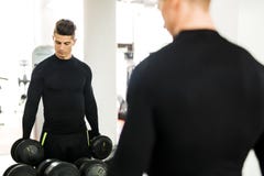 Νέο μυϊκό άτομο που επιλύει σε βάρη μιας γυμναστικής και ανύψωσης στοκ εικόνες με δικαίωμα ελεύθερης χρήσης Νέο μυϊκό άτομο που επιλύει σε βάρη μιας γυμναστικής και ανύψωσης στοκ εικόνες με δικαίωμα ελεύθερης χρήσης