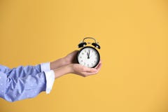 Νέο ξυπνητήρι εκμετάλλευσης γυναικών στο κίτρινο υπόβαθρο χρονικό λευκό αντικειμένου ανασκόπησης απομονωμένο έννοια στοκ εικόνα Νέο ξυπνητήρι εκμετάλλευσης γυναικών στο κίτρινο υπόβαθρο χρονικό λευκό αντικειμένου ανασκόπησης απομονωμένο έννοια στοκ εικόνα