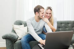 Νέο όμορφο ζεύγος που στηρίζεται στο σε απευθείας σύνδεση βίντεο καναπέδων και προσοχής από ένα lap-top στο καθιστικό στοκ εικόνα με δικαίωμα ελεύθερης χρήσης Νέο όμορφο ζεύγος που στηρίζεται στο σε απευθείας σύνδεση βίντεο καναπέδων και προσοχής από ένα lap-top στο καθιστικό στοκ εικόνα με δικαίωμα ελεύθερης χρήσης