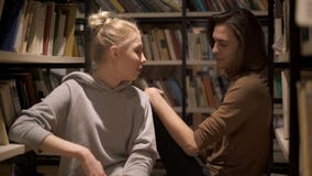 Νέοι σπουδαστές που κάθονται και που μιλούν μεταξύ των ραφιών απόθεμα βίντεο Νέοι σπουδαστές που κάθονται και που μιλούν μεταξύ των ραφιών απόθεμα βίντεο