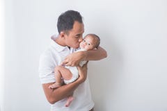 Νέος ασιατικός πατέρας που κρατά και που φιλά το λατρευτό μωρό στοκ φωτογραφίες με δικαίωμα ελεύθερης χρήσης Νέος ασιατικός πατέρας που κρατά και που φιλά το λατρευτό μωρό στοκ φωτογραφίες με δικαίωμα ελεύθερης χρήσης