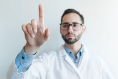 Νέος γιατρός που ωθεί από ένα δάχτυλο σχεδιάγραμμα για μια φουτουριστική ιατρική επιτροπή οθόνης στοκ εικόνα Νέος γιατρός που ωθεί από ένα δάχτυλο σχεδιάγραμμα για μια φουτουριστική ιατρική επιτροπή οθόνης στοκ εικόνα