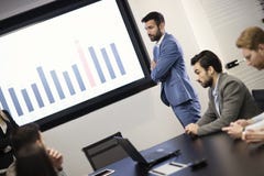 Νέος ελκυστικός επιχειρηματίας που παρουσιάζει παρουσίαση στους συναδέλφους του στοκ εικόνες με δικαίωμα ελεύθερης χρήσης Νέος ελκυστικός επιχειρηματίας που παρουσιάζει παρουσίαση στους συναδέλφους του στοκ εικόνες με δικαίωμα ελεύθερης χρήσης