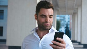 Νέος ελκυστικός επιχειρηματίας που χρησιμοποιεί Smartphone κοντά στο κτίριο γραφείων Να φανεί επιτυχής Γενειοφόρος όμορφη φθορά α απόθεμα βίντεο Νέος ελκυστικός επιχειρηματίας που χρησιμοποιεί Smartphone κοντά στο κτίριο γραφείων Να φανεί επιτυχής Γενειοφόρος όμορφη φθορά α απόθεμα βίντεο