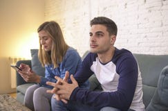Νέος καναπές καναπέδων ζευγών στο σπίτι με τη γυναίκα Διαδίκτυο και τον κινητό τηλεφωνικό εθισμό που αγνοεί το φίλο της που αισθά στοκ φωτογραφία Νέος καναπές καναπέδων ζευγών στο σπίτι με τη γυναίκα Διαδίκτυο και τον κινητό τηλεφωνικό εθισμό που αγνοεί το φίλο της που αισθά στοκ φωτογραφία