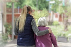 Νέος φροντιστής που περπατά με την ηλικιωμένη γυναίκα στον κήπο με το ελαφρύ υπόβαθρο στοκ εικόνες Νέος φροντιστής που περπατά με την ηλικιωμένη γυναίκα στον κήπο με το ελαφρύ υπόβαθρο στοκ εικόνες