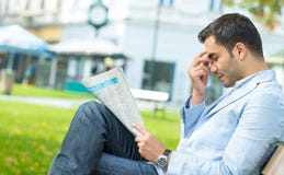 Νεαρός άνδρας με τις εφημερίδες μιας headashe εκμετάλλευσης στοκ φωτογραφία με δικαίωμα ελεύθερης χρήσης Νεαρός άνδρας με τις εφημερίδες μιας headashe εκμετάλλευσης στοκ φωτογραφία με δικαίωμα ελεύθερης χρήσης