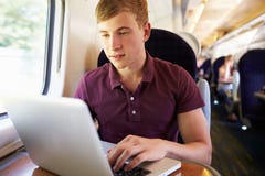 Νεαρός άνδρας που χρησιμοποιεί το lap-top στο ταξίδι τραίνων στοκ εικόνα με δικαίωμα ελεύθερης χρήσης Νεαρός άνδρας που χρησιμοποιεί το lap-top στο ταξίδι τραίνων στοκ εικόνα με δικαίωμα ελεύθερης χρήσης