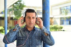 Νεαρός άνδρας χρησιμοποιώντας το smartphone και ακούοντας τη μουσική με το headp Στοκ εικόνα με δικαίωμα ελεύθερης χρήσης Νεαρός άνδρας χρησιμοποιώντας το smartphone και ακούοντας τη μουσική με το headp Στοκ εικόνα με δικαίωμα ελεύθερης χρήσης