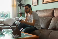 Νεαρός άνδρας που παίζει το τηλεοπτικό παιχνίδι που κρατά τον ασύρματο ελεγκτή στοκ φωτογραφίες με δικαίωμα ελεύθερης χρήσης Νεαρός άνδρας που παίζει το τηλεοπτικό παιχνίδι που κρατά τον ασύρματο ελεγκτή στοκ φωτογραφίες με δικαίωμα ελεύθερης χρήσης