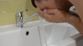 Νεαρός άνδρας που πλένει το πρόσωπό του στο λουτρό το πρωί Νεαρός άνδρας που πλένει το πρόσωπό του στο λουτρό το πρωί