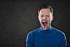 Νεαρός άνδρας σε ένα μπλε χασμουρητό πουλόβερ που κουράζεται και που τρυπιέται στοκ φωτογραφία με δικαίωμα ελεύθερης χρήσης Νεαρός άνδρας σε ένα μπλε χασμουρητό πουλόβερ που κουράζεται και που τρυπιέται στοκ φωτογραφία με δικαίωμα ελεύθερης χρήσης