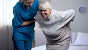 Νοσοκόμα που παίρνει την προσοχή για τη ηλικιωμένη κυρία που πάσχει από το χαμηλότερο πόνο στην πλάτη, ιατρικό κέντρο στοκ εικόνες με δικαίωμα ελεύθερης χρήσης Νοσοκόμα που παίρνει την προσοχή για τη ηλικιωμένη κυρία που πάσχει από το χαμηλότερο πόνο στην πλάτη, ιατρικό κέντρο στοκ εικόνες με δικαίωμα ελεύθερης χρήσης