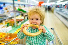 Νόστιμο κουλούρι Bagel δαγκωμάτων αγοριών με το σουσάμι στην υπεραγορά r Αγορές αγορών για τα τρόφιμα Τρόφιμα παιδιών στοκ φωτογραφία με δικαίωμα ελεύθερης χρήσης Νόστιμο κουλούρι Bagel δαγκωμάτων αγοριών με το σουσάμι στην υπεραγορά r Αγορές αγορών για τα τρόφιμα Τρόφιμα παιδιών στοκ φωτογραφία με δικαίωμα ελεύθερης χρήσης