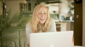 Ξανθή γυναίκα που εξετάζει το lap-top της που γελά και που φιλμ μικρού μήκους Ξανθή γυναίκα που εξετάζει το lap-top της που γελά και που φιλμ μικρού μήκους