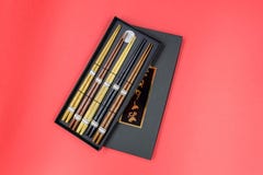 Ξύλινα chopsticks στο μαύρο κουτί που απομονώνεται στο κόκκινο υπόβαθρο στοκ φωτογραφίες με δικαίωμα ελεύθερης χρήσης Ξύλινα chopsticks στο μαύρο κουτί που απομονώνεται στο κόκκινο υπόβαθρο στοκ φωτογραφίες με δικαίωμα ελεύθερης χρήσης