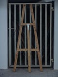 Ξύλινο ψηλό easel που στέκεται ενάντια σε μια πόρτα γκαράζ μετάλλων στο λευκό στοκ εικόνα Ξύλινο ψηλό easel που στέκεται ενάντια σε μια πόρτα γκαράζ μετάλλων στο λευκό στοκ εικόνα