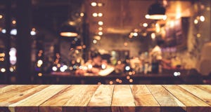 Ξύλινος φραγμός επιτραπέζιων κορυφών με το υπόβαθρο καφέδων νύχτας θαμπάδων Ξύλινος φραγμός επιτραπέζιων κορυφών με το υπόβαθρο καφέδων νύχτας θαμπάδων