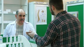 Ο ανώτερος φαρμακοποιός και ο νέος αρσενικός πελάτης έχουν τη σύγκρουση στο φαρμακείο στοκ εικόνα Ο ανώτερος φαρμακοποιός και ο νέος αρσενικός πελάτης έχουν τη σύγκρουση στο φαρμακείο στοκ εικόνα