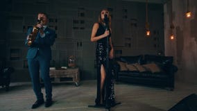 Ο αοιδός της Jazz στο καμμένος φόρεμα αποδίδει στη σκηνή με τη ζωντανή συναυλία saxophonist απόθεμα βίντεο Ο αοιδός της Jazz στο καμμένος φόρεμα αποδίδει στη σκηνή με τη ζωντανή συναυλία saxophonist απόθεμα βίντεο