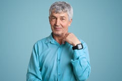 Ο απομονωμένος πυροβολισμός του όμορφου ανώτερου ατόμου φορά το μπλε κομψό πουκάμισο, wristwatch, έχει ζαρώσει το πρόσωπο, θέτει στοκ φωτογραφία με δικαίωμα ελεύθερης χρήσης Ο απομονωμένος πυροβολισμός του όμορφου ανώτερου ατόμου φορά το μπλε κομψό πουκάμισο, wristwatch, έχει ζαρώσει το πρόσωπο, θέτει στοκ φωτογραφία με δικαίωμα ελεύθερης χρήσης