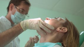 Ο αρσενικός οδοντίατρος μεταχειρίζεται ένα δόντι του θηλυκού ασθενή χρησιμοποιώντας τον οδοντικό εξοπλισμό στην αρχή απόθεμα βίντεο Ο αρσενικός οδοντίατρος μεταχειρίζεται ένα δόντι του θηλυκού ασθενή χρησιμοποιώντας τον οδοντικό εξοπλισμό στην αρχή απόθεμα βίντεο