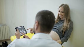 Ο γιατρός παρουσιάζει μια εικόνα ενός υπερήχου σε μια ταμπλέτα σε μια έγκυο γυναίκα απόθεμα βίντεο Ο γιατρός παρουσιάζει μια εικόνα ενός υπερήχου σε μια ταμπλέτα σε μια έγκυο γυναίκα απόθεμα βίντεο