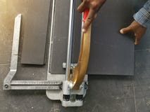 Ο εργάτης οικοδομών κόβει τα κεραμίδια στο σπίτι στοκ φωτογραφίες Ο εργάτης οικοδομών κόβει τα κεραμίδια στο σπίτι στοκ φωτογραφίες