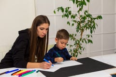 Ο θηλυκός δάσκαλος διδάσκει ένα μικρό αγόρι για να σύρει στον πίνακα στοκ εικόνες με δικαίωμα ελεύθερης χρήσης Ο θηλυκός δάσκαλος διδάσκει ένα μικρό αγόρι για να σύρει στον πίνακα στοκ εικόνες με δικαίωμα ελεύθερης χρήσης
