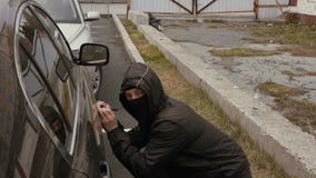 Ο κλέφτης ατόμων στη μαύρη μάσκα στο πρόσωπο και η κουκούλα στην επικεφαλής προσπάθεια κλέβουν το αυτοκίνητο στην οδό πόλεων απόθεμα βίντεο Ο κλέφτης ατόμων στη μαύρη μάσκα στο πρόσωπο και η κουκούλα στην επικεφαλής προσπάθεια κλέβουν το αυτοκίνητο στην οδό πόλεων απόθεμα βίντεο
