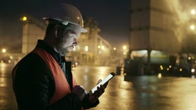 Ο μηχανικός hardhat με έναν υπολογιστή ταμπλετών εξετάζει το φορτηγό στο βαρύ εργοστάσιο βιομηχανίας Ο μηχανικός hardhat με έναν υπολογιστή ταμπλετών εξετάζει το φορτηγό στο βαρύ εργοστάσιο βιομηχανίας