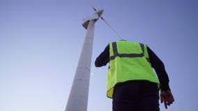 Ο μηχανικός με βεβαιότητα στην κατεύθυνση του ανεμόμυλου μια κίτρινη φανέλλα και φορά στο κεφάλι του το άσπρο κράνος απόθεμα βίντεο Ο μηχανικός με βεβαιότητα στην κατεύθυνση του ανεμόμυλου μια κίτρινη φανέλλα και φορά στο κεφάλι του το άσπρο κράνος απόθεμα βίντεο