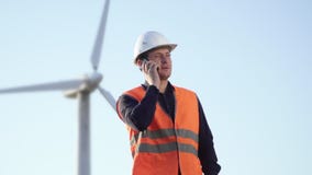 Ο μηχανικός της καυκάσιας εμφάνισης είναι κοντά στον ανεμόμυλο και την ομιλία σε ένα τηλέφωνο κυττάρων φιλμ μικρού μήκους Ο μηχανικός της καυκάσιας εμφάνισης είναι κοντά στον ανεμόμυλο και την ομιλία σε ένα τηλέφωνο κυττάρων φιλμ μικρού μήκους
