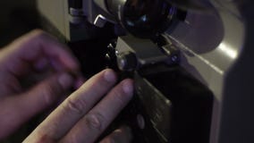Ο μηχανικός χρεώνει την ταινία σε έναν παλαιό προβολέα ταινιών Κινηματογράφηση σε πρώτο πλάνο ενός εξελίκτρου με μια ταινία φιλμ μικρού μήκους Ο μηχανικός χρεώνει την ταινία σε έναν παλαιό προβολέα ταινιών Κινηματογράφηση σε πρώτο πλάνο ενός εξελίκτρου με μια ταινία φιλμ μικρού μήκους
