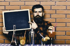Ο μπάρμαν, bartender ή hipster κρατά τη διαφήμιση φραγμών Έννοια επιλογών φραγμών Ο μπάρμαν με τη γενειάδα και το σοβαρό πρόσωπο στοκ εικόνες Ο μπάρμαν, bartender ή hipster κρατά τη διαφήμιση φραγμών Έννοια επιλογών φραγμών Ο μπάρμαν με τη γενειάδα και το σοβαρό πρόσωπο στοκ εικόνες