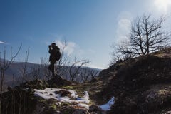 Ο μπλε ουρανός και ο ήλιος καίγονται πίσω από έναν οδοιπόρο που στέκεται στην κορυφή του βουνού στοκ εικόνα με δικαίωμα ελεύθερης χρήσης Ο μπλε ουρανός και ο ήλιος καίγονται πίσω από έναν οδοιπόρο που στέκεται στην κορυφή του βουνού στοκ εικόνα με δικαίωμα ελεύθερης χρήσης