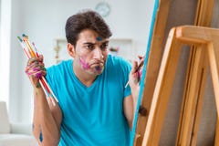 Ο νέος αστείος καλλιτέχνης που εργάζεται στη νέα ζωγραφική στο στούντιό του στοκ εικόνες Ο νέος αστείος καλλιτέχνης που εργάζεται στη νέα ζωγραφική στο στούντιό του στοκ εικόνες