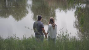 Ο νεαρός άνδρας και η γυναίκα που στέκονται στη λίμνη και εξετάζουν τα χέρια εκμετάλλευσης απόστασης απόθεμα βίντεο Ο νεαρός άνδρας και η γυναίκα που στέκονται στη λίμνη και εξετάζουν τα χέρια εκμετάλλευσης απόστασης απόθεμα βίντεο